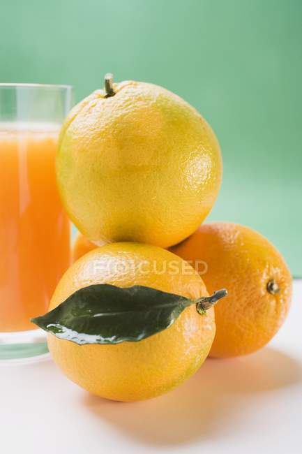 Vaso de jugo fresco con naranjas - foto de stock