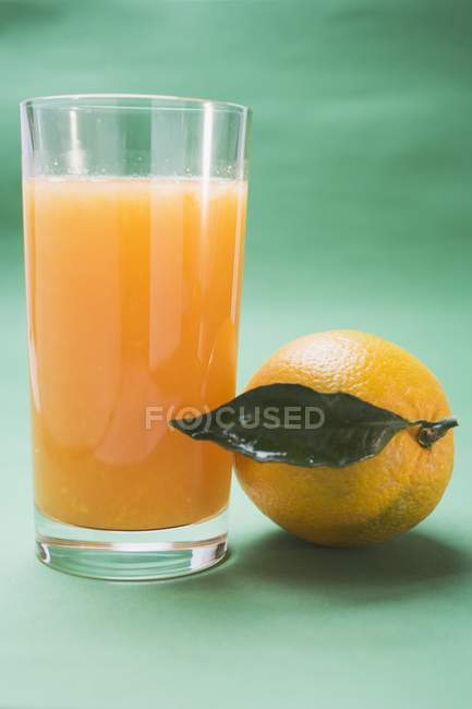 Bicchiere di succo e arancia con foglia — Foto stock