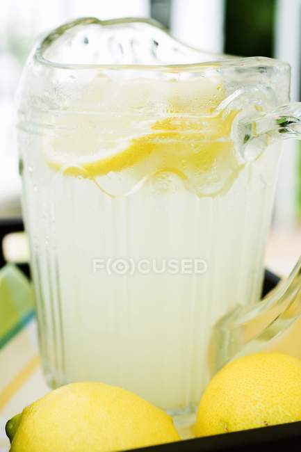 Citronnade dans une cruche avec des tranches de citron — Photo de stock