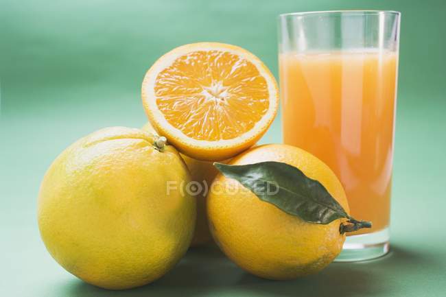 Naranjas frescas maduras y un vaso de jugo - foto de stock