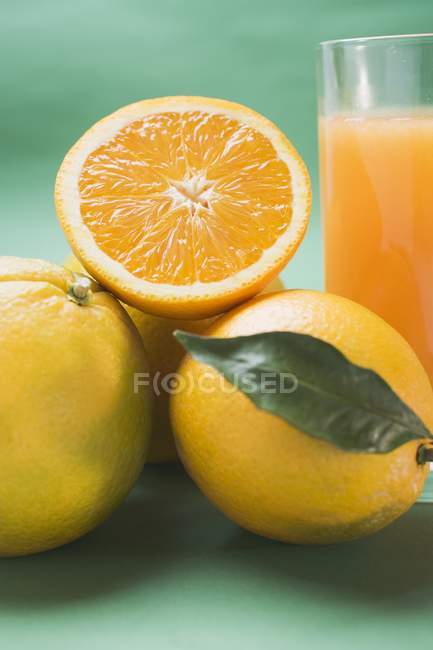 Fresh ripe oranges and glass of juice — Stock Photo