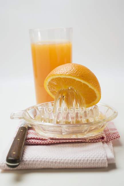 Vaso de zumo de naranja con exprimidor de cítricos - foto de stock