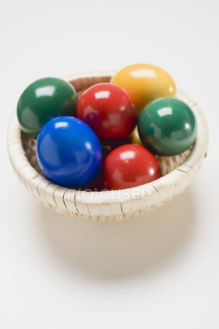 Coloured eggs in basket — Stock Photo