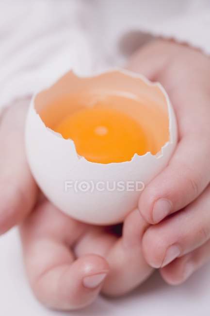 Main d'enfant tenant un œuf cru — Photo de stock