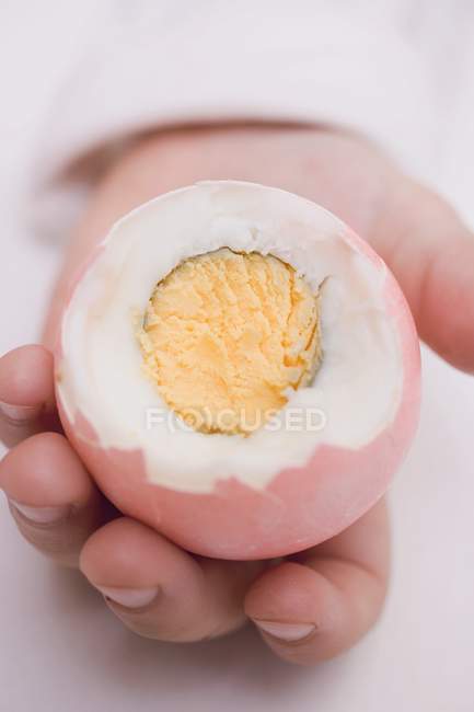 Niño mano sosteniendo huevo hervido - foto de stock