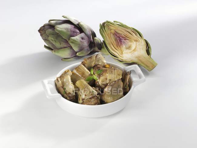 Marinated artichokes  on white plate  over white surface — Stock Photo
