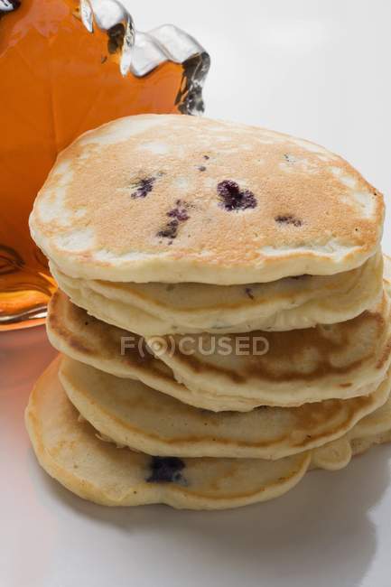 Pancakes in front of bottle of maple syrup — Stock Photo