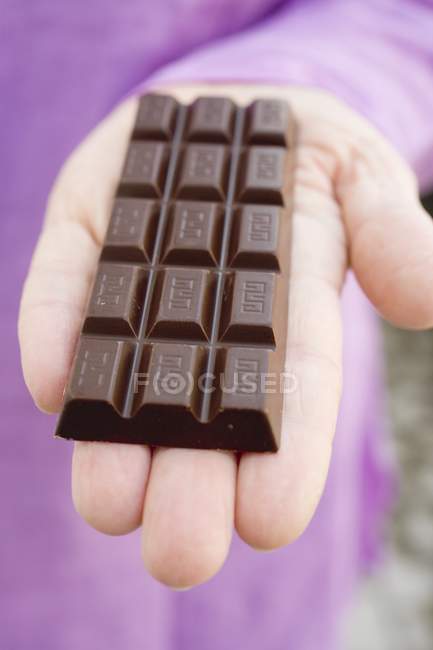 Main femelle tenant barre de chocolat — Photo de stock
