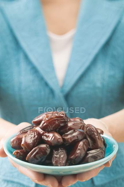 Woman holding plate of dates — Stock Photo