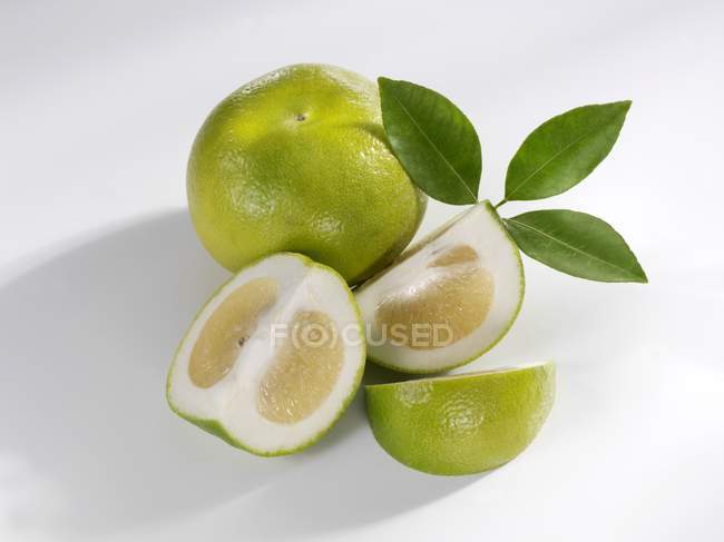 Green grapefruit with slices and leaves — Stock Photo