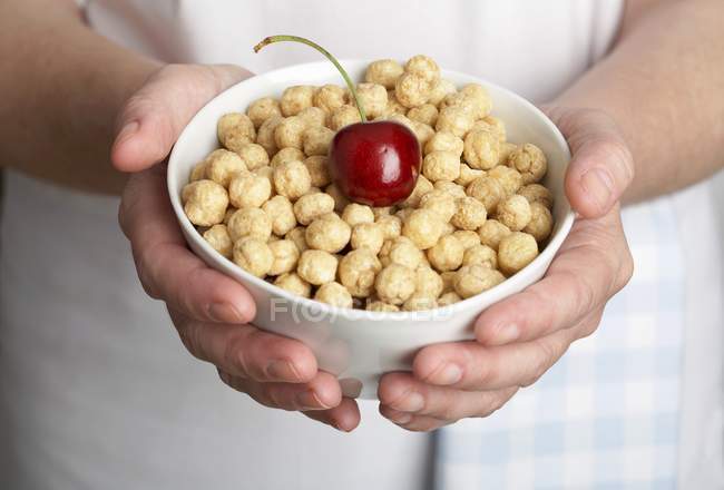Hands holding bowl of toasted rice — Stock Photo