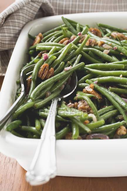 Green beans with bacon and pecans on white plate with spoon — Stock Photo