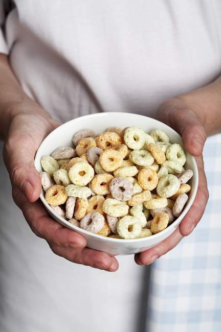 Hands holding a bowl of multi-grain cereal loops — Stock Photo