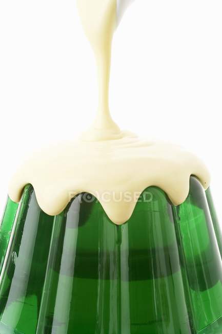 Pouring custard over jelly — Stock Photo