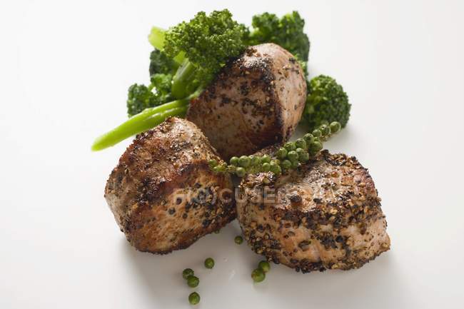 Medallones de cerdo con granos de pimienta verde - foto de stock