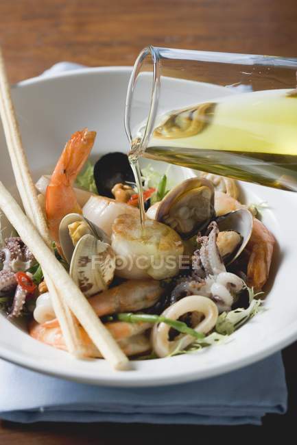 Pouring olive oil over seafood salad — Stock Photo
