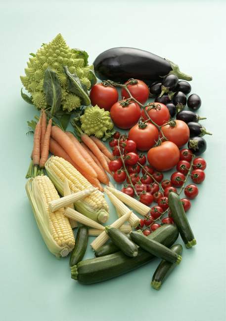 Petits et grands légumes sur surface verte — Photo de stock