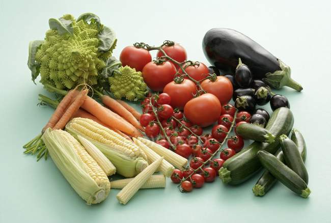 Маленькие и большие овощи на светло-зеленой поверхности — стоковое фото