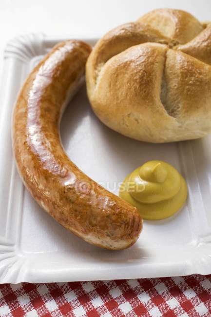 Sausage with mustard and bread roll — Stock Photo