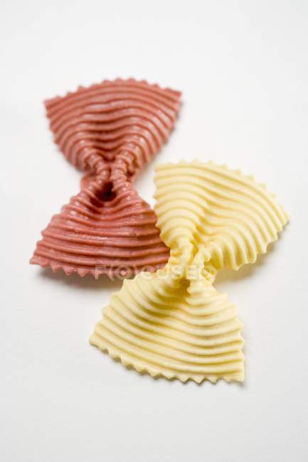 Two red and yellow farfalle pasta pieces — Stock Photo