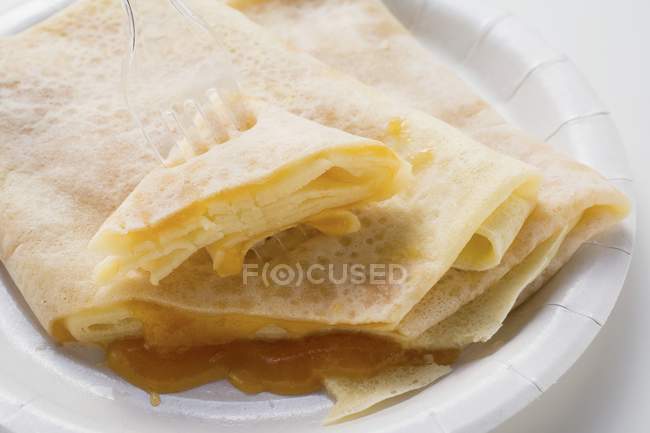 Closeup view of crepes with apricot jam on paper plate — Stock Photo