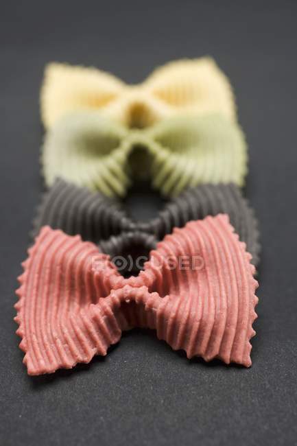 Coloured farfalle pasta piecesin row — Stock Photo
