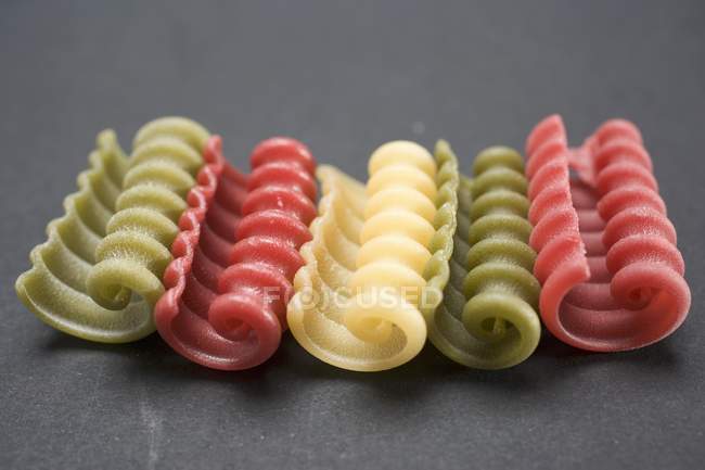 Coloured riccioli pasta pieces in row — Stock Photo