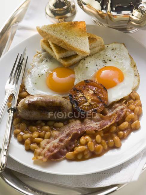 Englisches Frühstück auf weißem Teller mit Gabel und Messer — Stockfoto