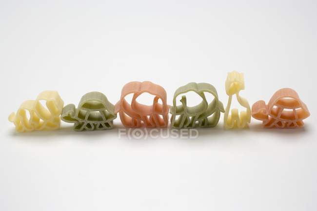 Coloured animal-shaped pasta in row — Stock Photo