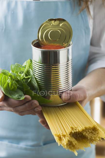 Woman holding tomato puree and spaghetti — Stock Photo
