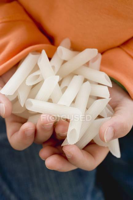 Child holding dried penne pasta — Stock Photo