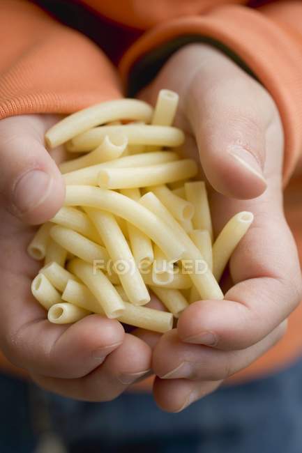 Child holding macaroni pasta — Stock Photo