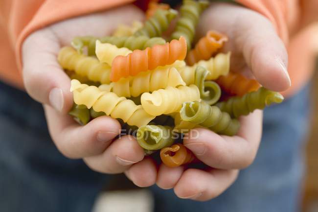 Дитина тримає кольорові спіральні макарони — стокове фото