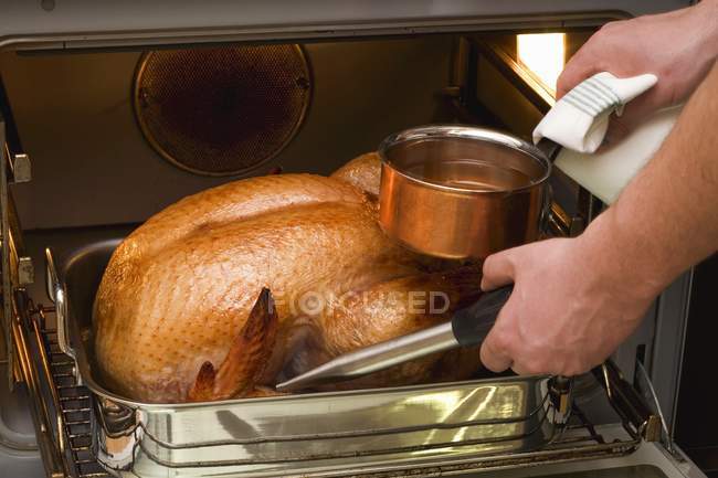 Basting turkey with roasting juices — Stock Photo