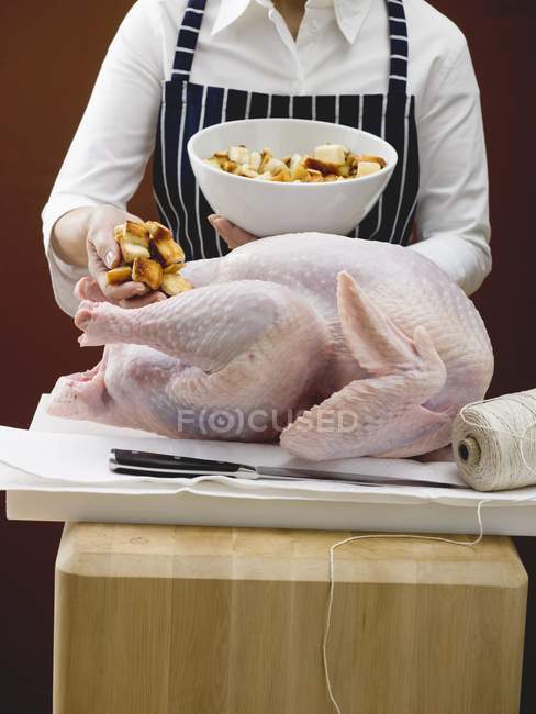 Woman Stuffing turkey with bread cubes — Stock Photo