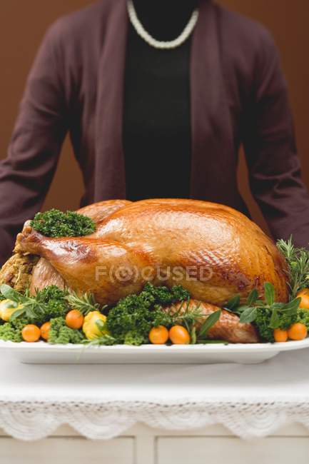 Woman holding stuffed roast turkey — Stock Photo