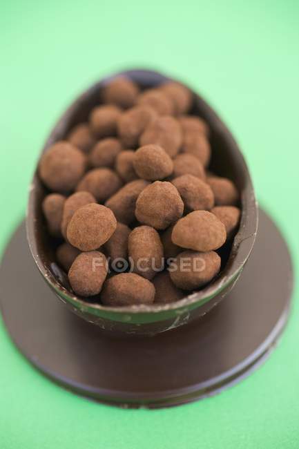 Closeup view of chocolate egg half filled with small truffles — Stock Photo