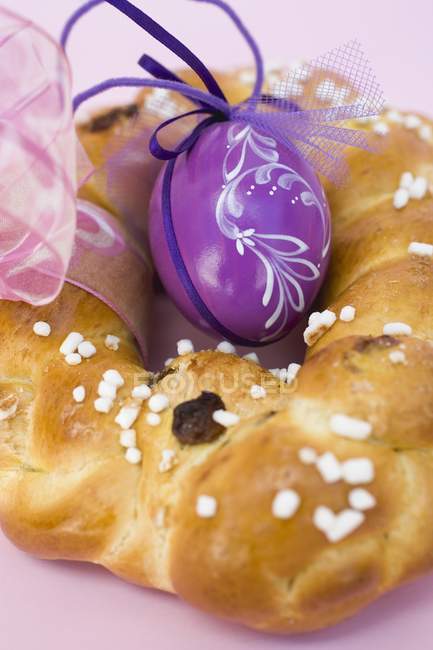 Крупный план плетеного хлебного кольца с фиолетовым пасхальным яйцом — стоковое фото