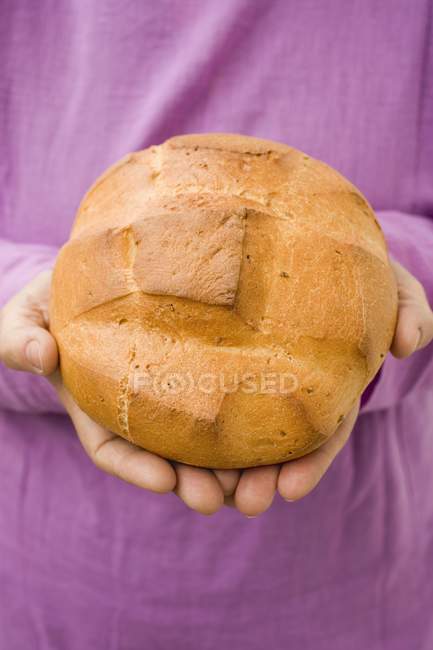Closeup view of hands holding round bread loaf — Stock Photo