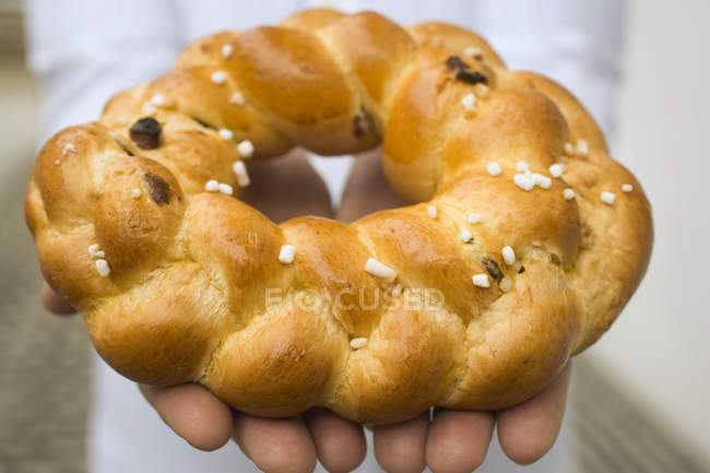 Primo piano vista ritagliata delle mani che tengono anello di pane intrecciato con zucchero di perla — Foto stock