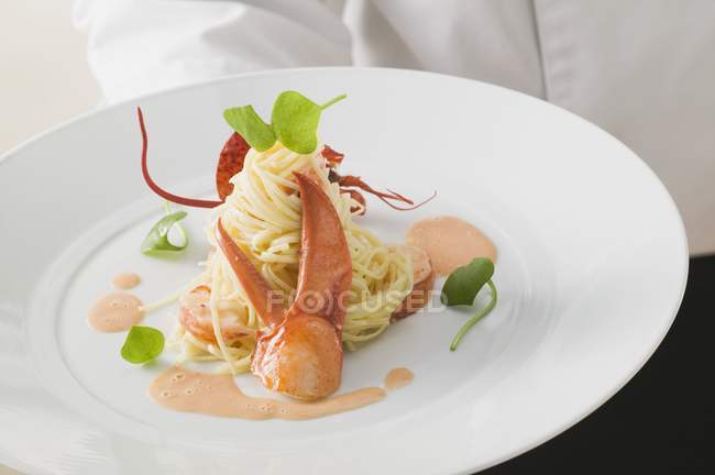 Waiter serving linguine pasta with lobster — Stock Photo