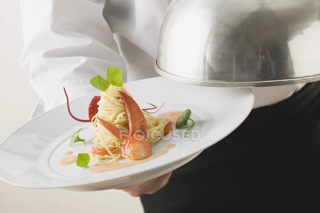 Camarero que sirve pasta linguine con langosta - foto de stock