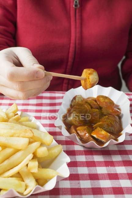 Woman eating currywurst with chips — Stock Photo