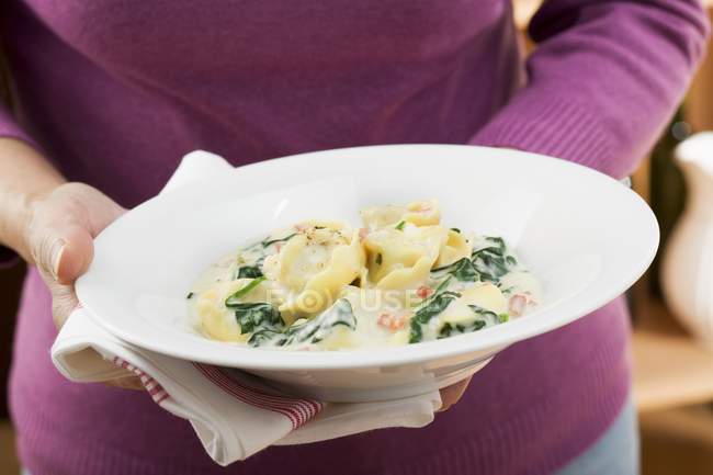 Frau hält Tortellini-Nudeln mit Spinat — Stockfoto