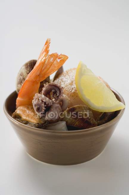 Vue rapprochée des fruits de mer avec coin de citron dans un bol brun — Photo de stock
