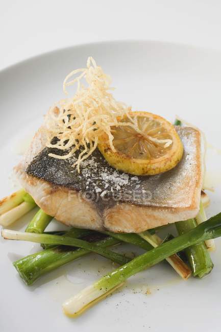 Fried fish fillet on spring onions — Stock Photo