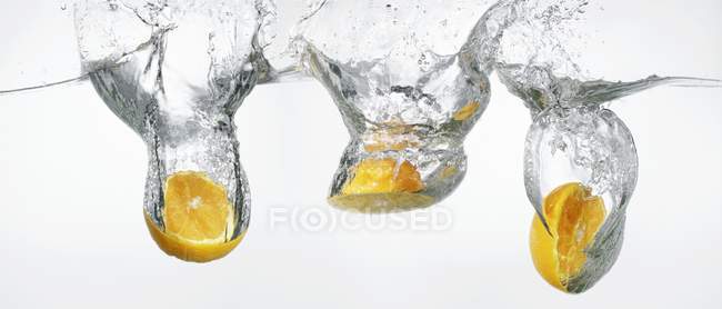 Апельсины падают в воду — стоковое фото