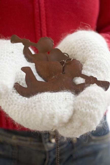Hands in mittens holding decorative angels — Stock Photo