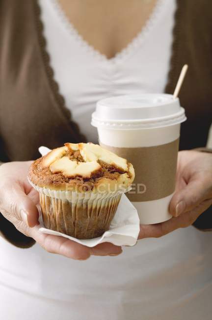 Mulher segurando muffin e xícara de café — Fotografia de Stock