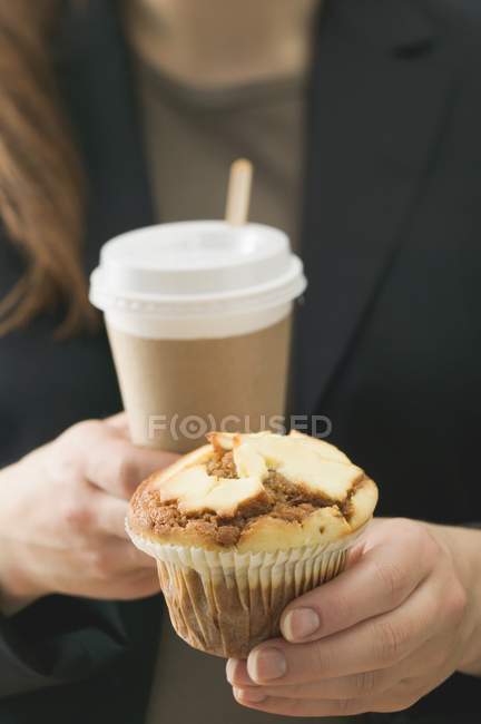 Жінка тримає кекс і чашку кави — стокове фото